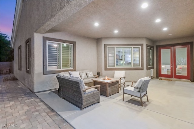 patio terrace at dusk featuring french doors and an outdoor living space with a fire pit