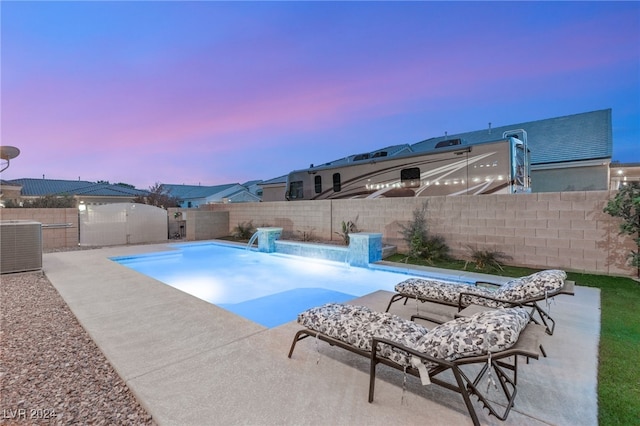 pool at dusk featuring cooling unit and pool water feature