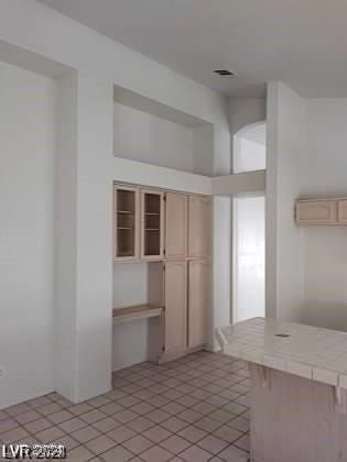 kitchen with tile countertops, light tile patterned floors, and a wall mounted air conditioner