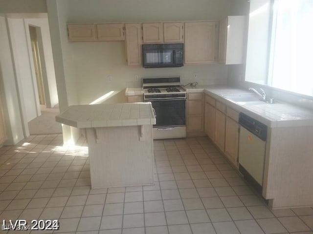 kitchen featuring light brown cabinetry, sink, dishwasher, tile countertops, and range