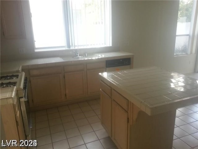 kitchen featuring a wealth of natural light, a center island, tile counters, and white gas stove