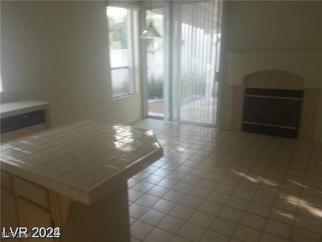 unfurnished living room with tile patterned floors, a fireplace, and a wealth of natural light