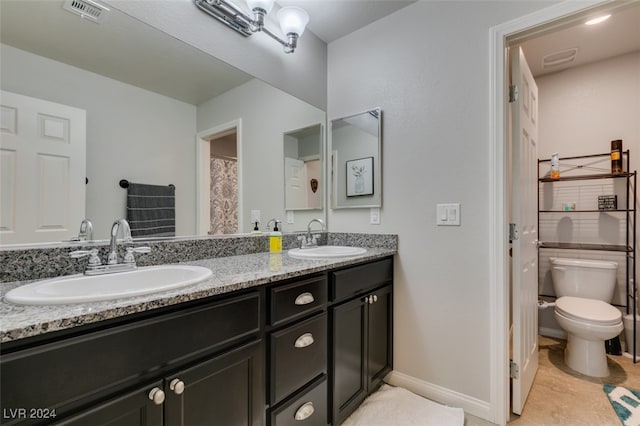 bathroom with toilet, vanity, and tile patterned floors