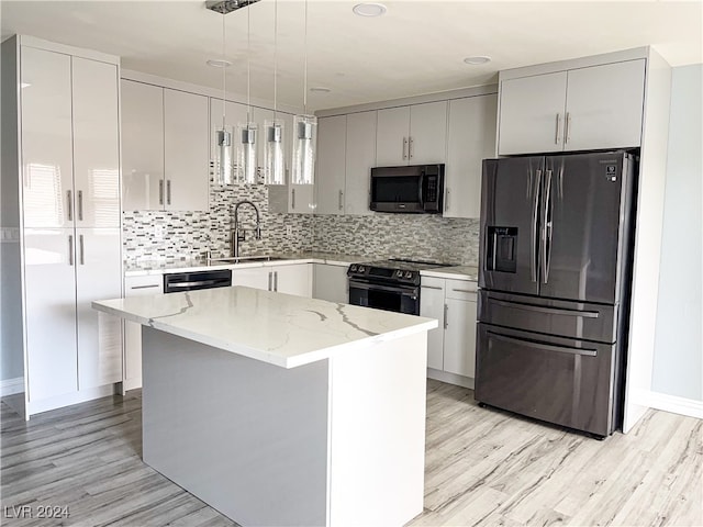 kitchen featuring stainless steel appliances, sink, pendant lighting, light hardwood / wood-style flooring, and a kitchen island