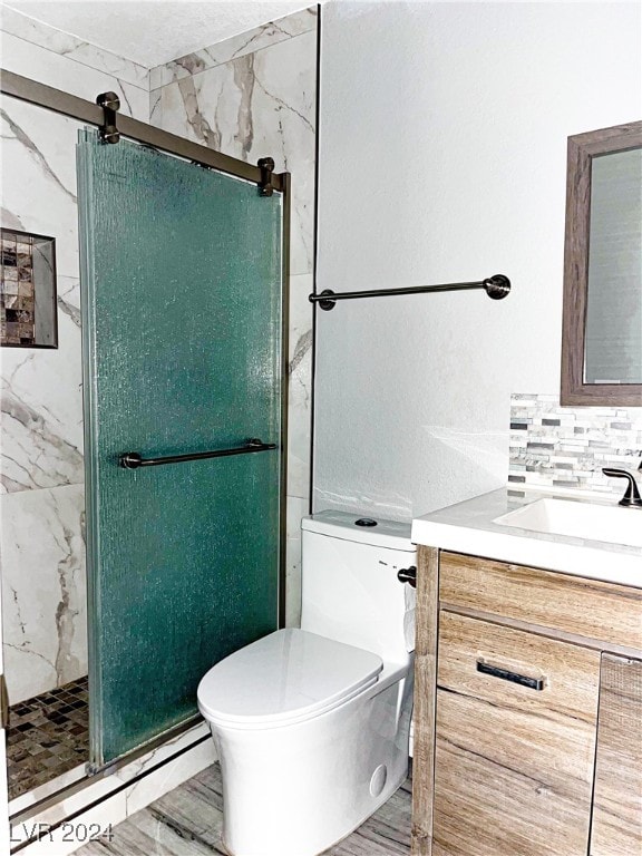 bathroom with vanity, backsplash, wood-type flooring, toilet, and a shower with shower door