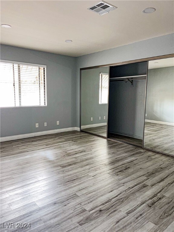 unfurnished bedroom featuring a closet, wood-type flooring, and multiple windows