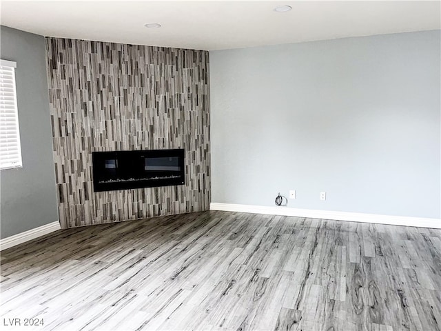 unfurnished living room with light hardwood / wood-style floors and a tiled fireplace