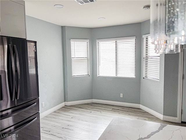 kitchen with a notable chandelier, black refrigerator, and light hardwood / wood-style flooring