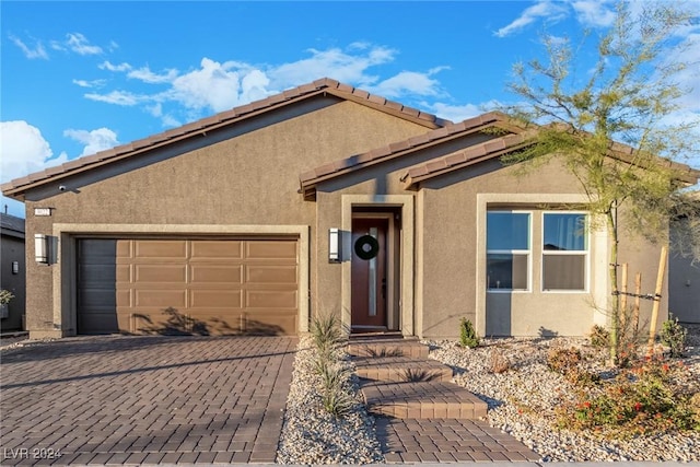 single story home with stucco siding, decorative driveway, and a garage
