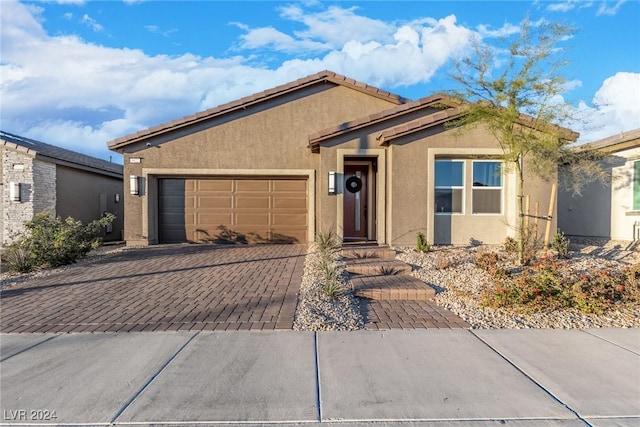 ranch-style house featuring a garage, stucco siding, and decorative driveway