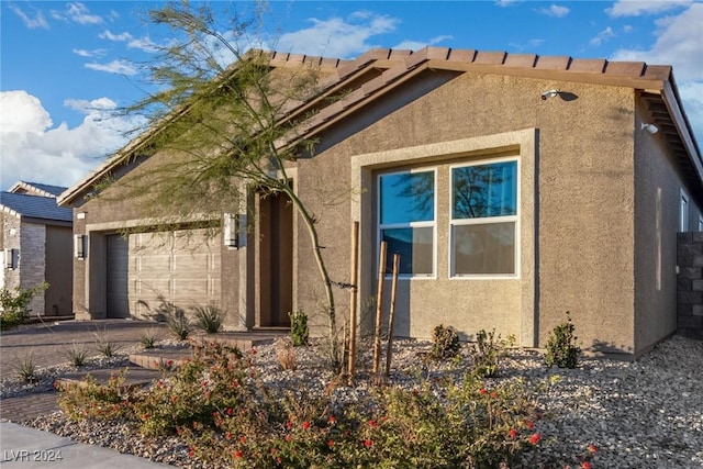 view of home's exterior with a garage, stucco siding, and driveway