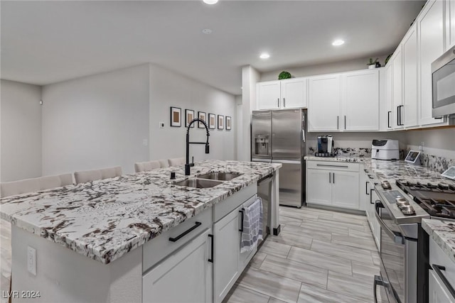 kitchen featuring recessed lighting, a sink, appliances with stainless steel finishes, and light stone countertops