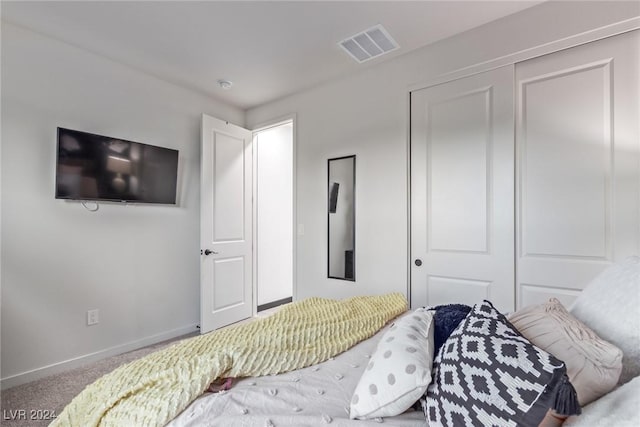 carpeted bedroom with visible vents, baseboards, and a closet