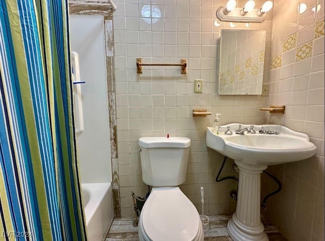 bathroom with shower / bath combination with curtain, toilet, and tile walls