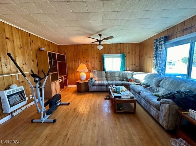 living room featuring hardwood / wood-style flooring, ceiling fan, wood walls, and heating unit