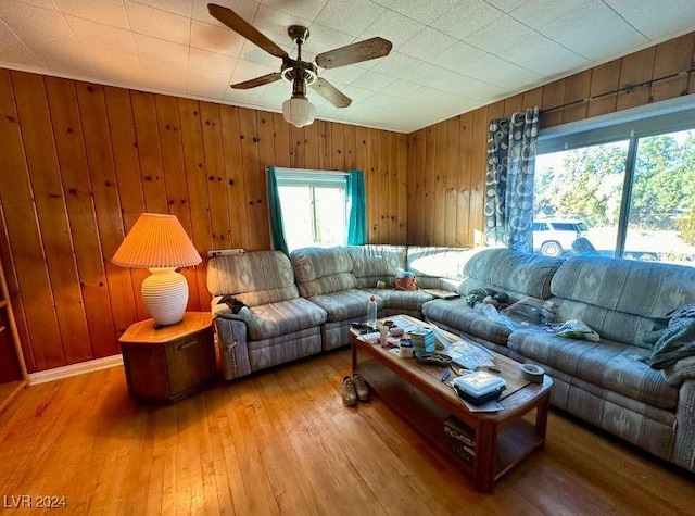 living room featuring hardwood / wood-style flooring, ceiling fan, and wood walls