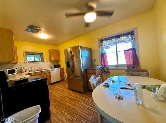 kitchen with plenty of natural light, light wood-type flooring, white appliances, and tasteful backsplash