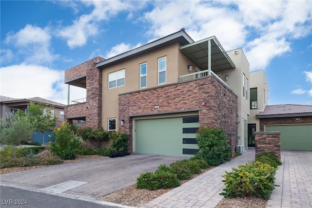 view of front of house with central air condition unit, a balcony, and a garage