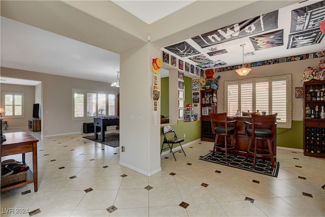 dining area featuring an inviting chandelier, bar, and light tile patterned floors