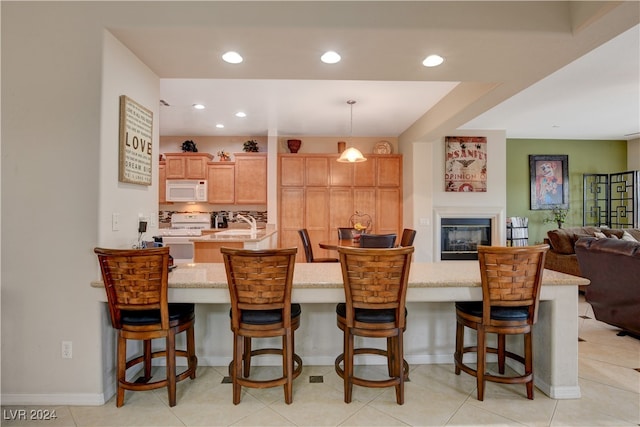 kitchen featuring a kitchen breakfast bar, decorative light fixtures, white appliances, and light tile patterned floors