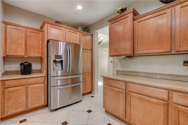 kitchen featuring stainless steel refrigerator with ice dispenser, light tile patterned flooring, and light stone counters