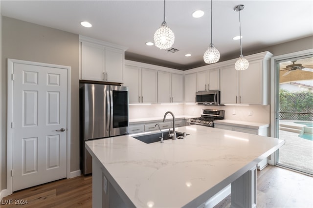 kitchen featuring sink, a kitchen island with sink, pendant lighting, appliances with stainless steel finishes, and white cabinetry