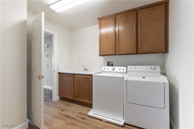 laundry room featuring cabinets, sink, light wood-type flooring, and washer and clothes dryer