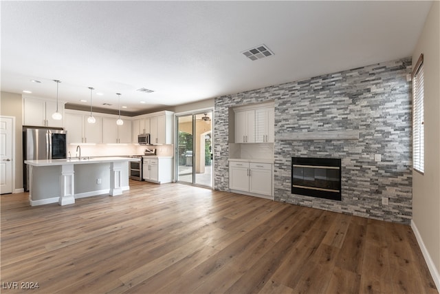 unfurnished living room featuring a stone fireplace, light hardwood / wood-style flooring, and sink