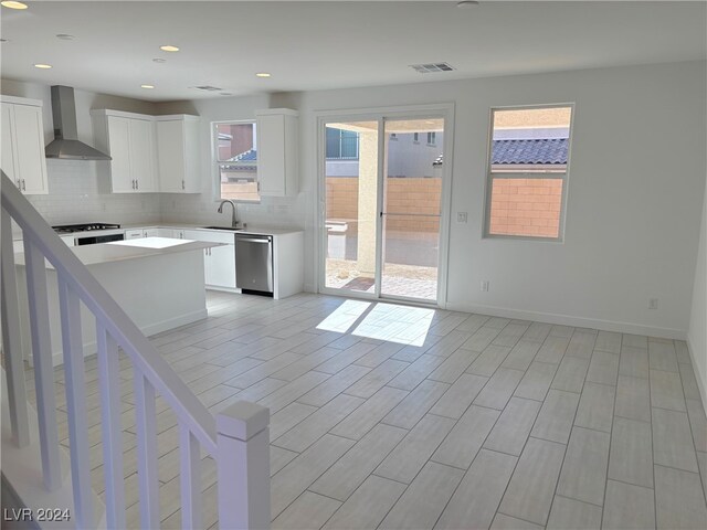 kitchen with dishwasher, a center island, white cabinets, sink, and wall chimney exhaust hood