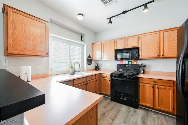 kitchen featuring kitchen peninsula, track lighting, light hardwood / wood-style flooring, black appliances, and sink