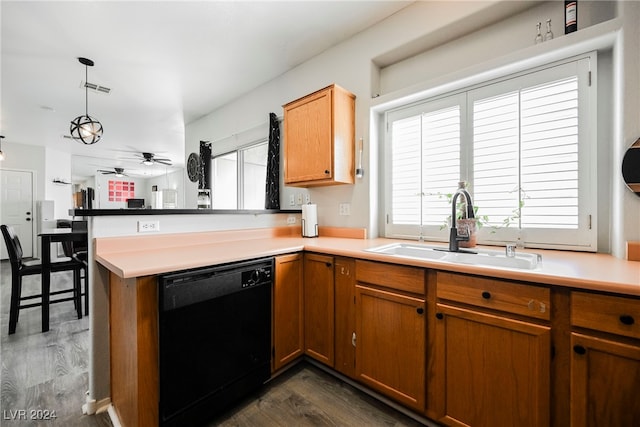 kitchen with black dishwasher, sink, dark hardwood / wood-style flooring, kitchen peninsula, and pendant lighting