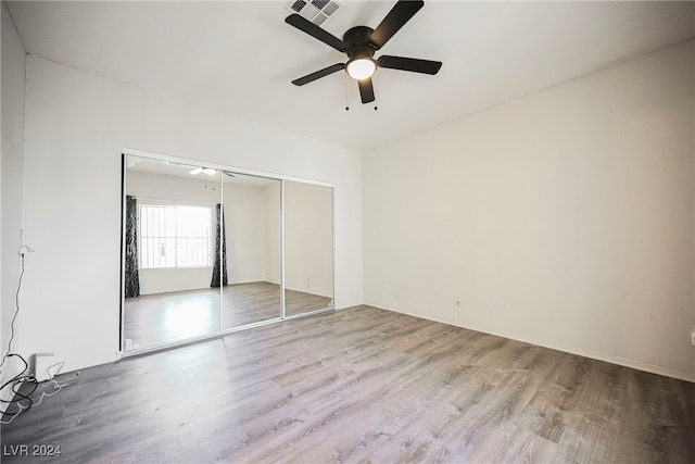 unfurnished bedroom with a closet, light wood-type flooring, and ceiling fan