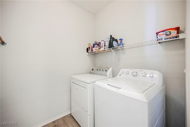 clothes washing area with washer and clothes dryer and hardwood / wood-style floors