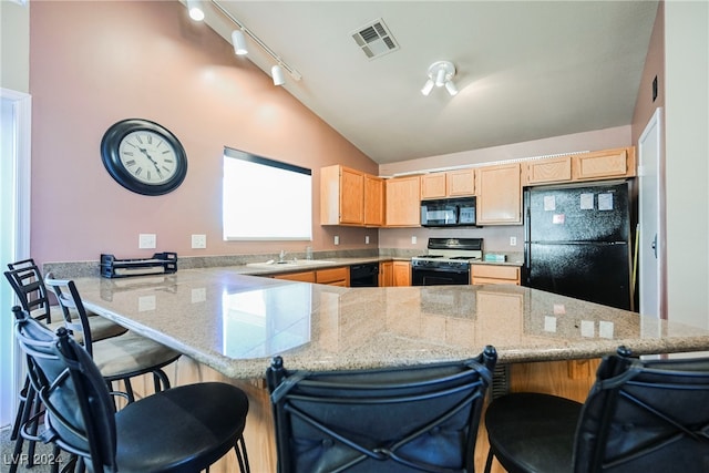 kitchen with kitchen peninsula, lofted ceiling, light brown cabinets, a kitchen breakfast bar, and black appliances