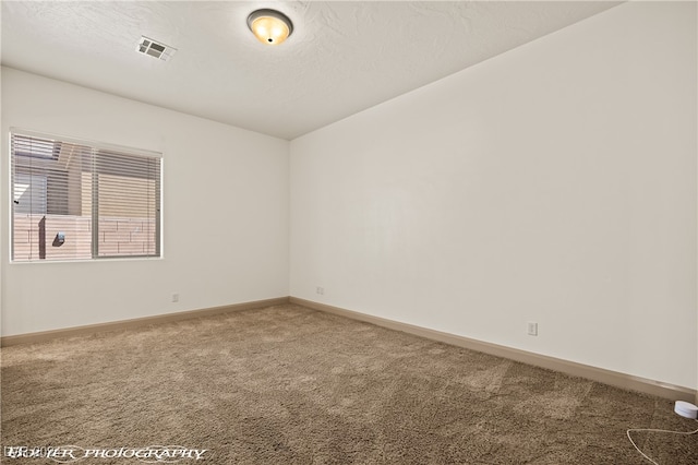 carpeted empty room with a textured ceiling