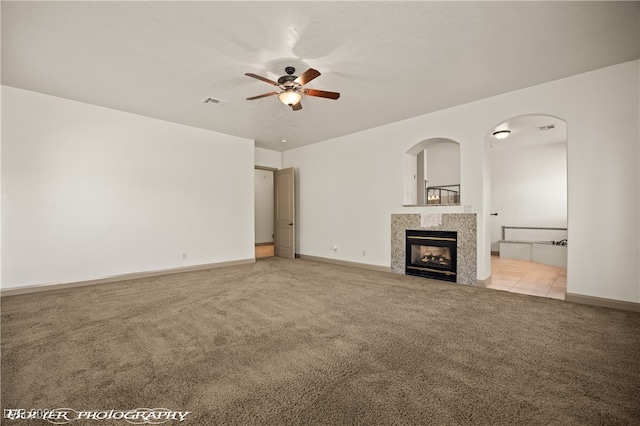 unfurnished living room with light carpet, a fireplace, and ceiling fan