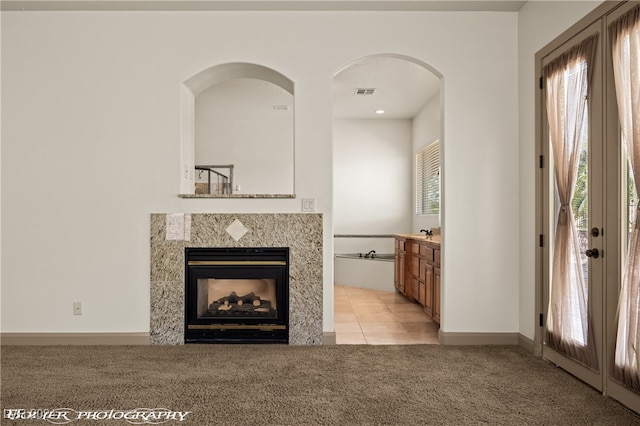 unfurnished living room with a tiled fireplace and light colored carpet