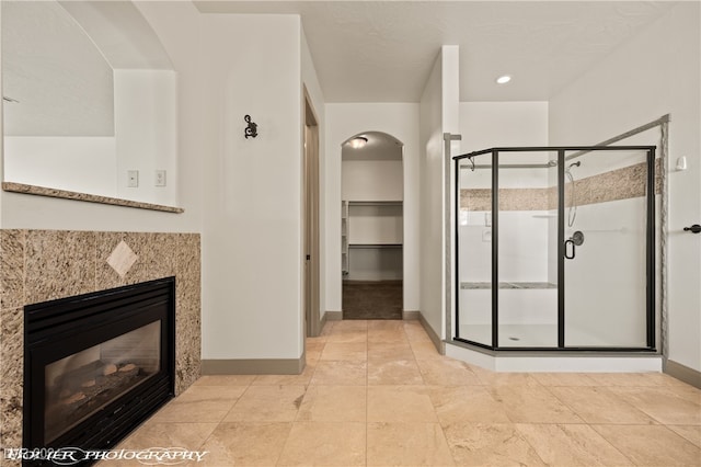 bathroom featuring a shower with shower door and a tile fireplace