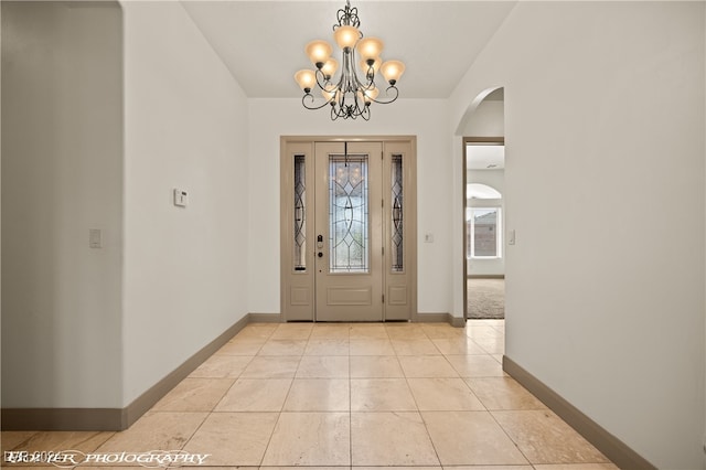 tiled entryway featuring vaulted ceiling and a notable chandelier