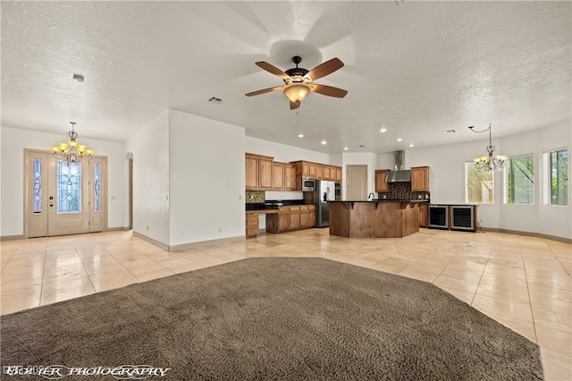 unfurnished living room featuring a textured ceiling, light tile patterned flooring, and ceiling fan with notable chandelier