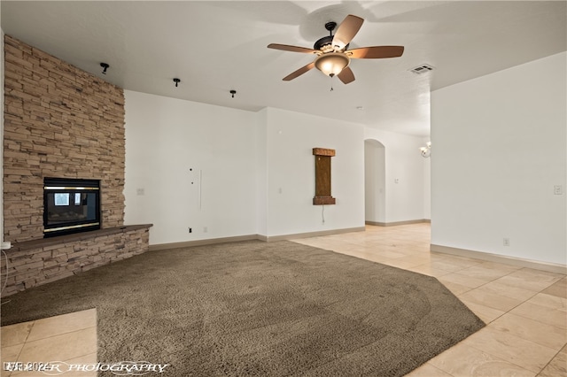 unfurnished living room with ceiling fan, a fireplace, and light colored carpet