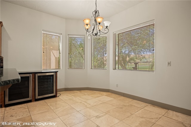 unfurnished dining area featuring an inviting chandelier, a healthy amount of sunlight, and beverage cooler