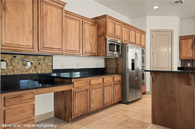 kitchen featuring light tile patterned flooring, backsplash, a textured ceiling, stainless steel appliances, and dark stone countertops