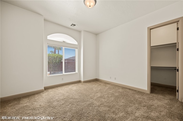 unfurnished bedroom with a walk in closet, carpet flooring, and a closet