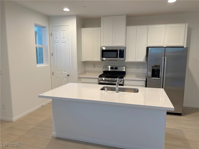 kitchen with sink, white cabinetry, stainless steel appliances, and a kitchen island with sink