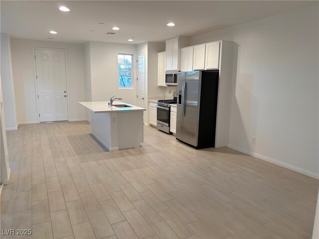 kitchen featuring a center island with sink, white cabinets, sink, and appliances with stainless steel finishes