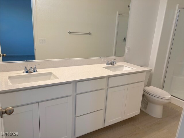 bathroom with hardwood / wood-style flooring, vanity, an enclosed shower, and toilet