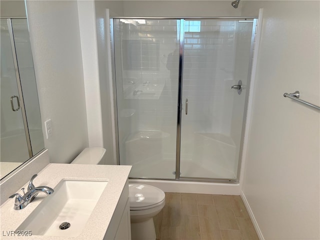 bathroom featuring vanity, wood-type flooring, an enclosed shower, and toilet