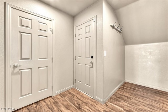 corridor with lofted ceiling and hardwood / wood-style flooring