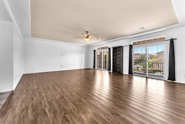 empty room with ceiling fan, a tray ceiling, and hardwood / wood-style floors